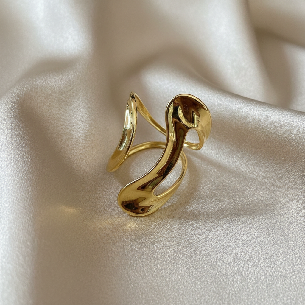 The Aurea Ring from Chica Chica Jewelry with a wavy design on a beige fabric background