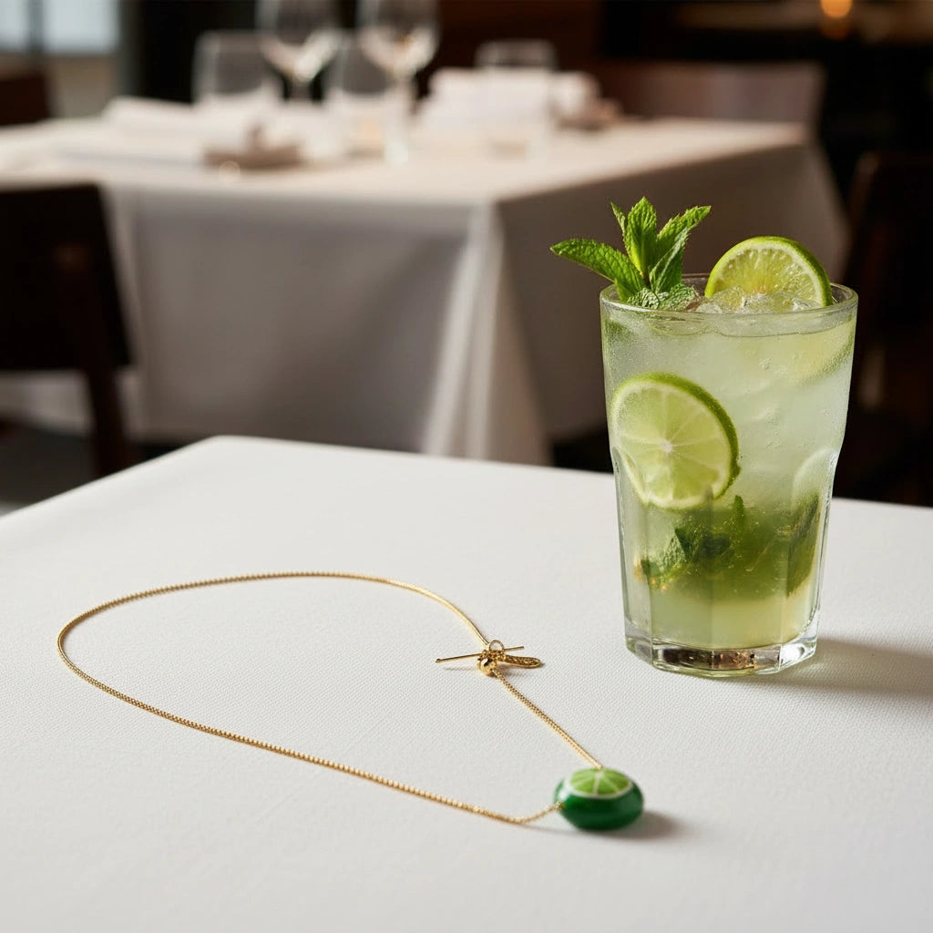 Tutti Frutti Lime Necklace with a hand-painted lime charm on a delicate gold-plated chain styled beside a fresh lime cocktail for a playful, modern look.