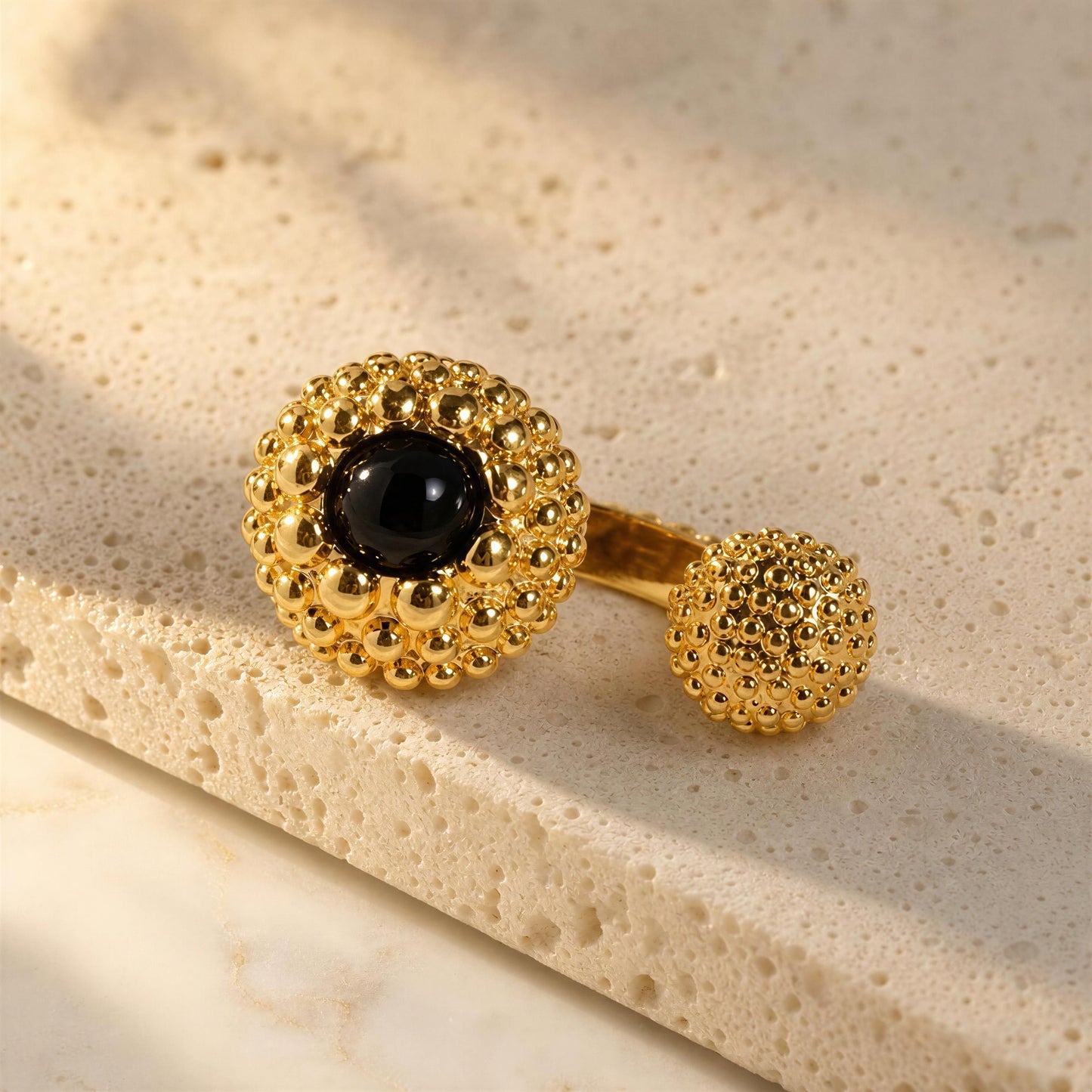 Chica Chica Jewelry, Nero Ring, displayed on a textured beige stone surface.