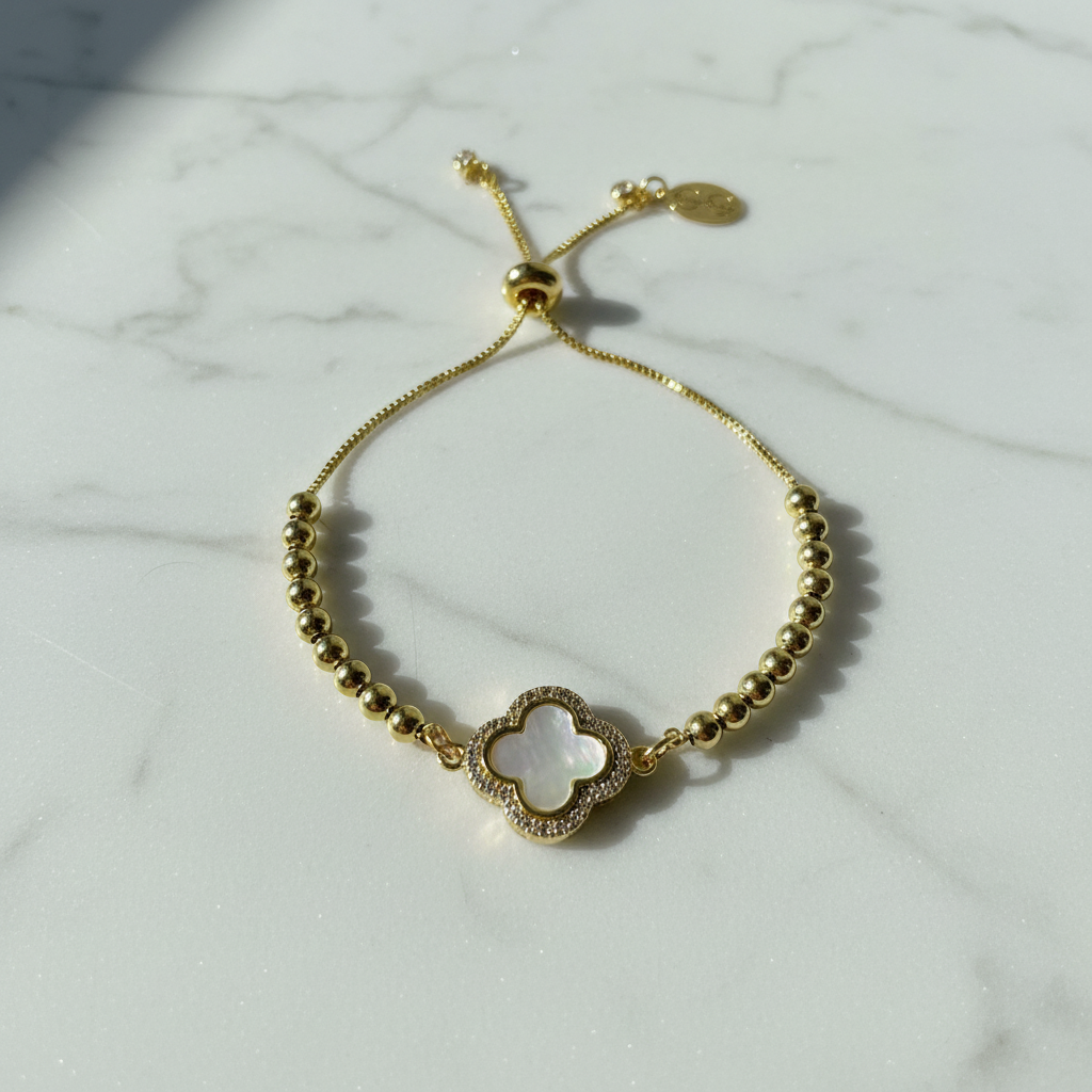 Gold Eterna Clover Bracelet - with a clover-shaped charm on a marble surface