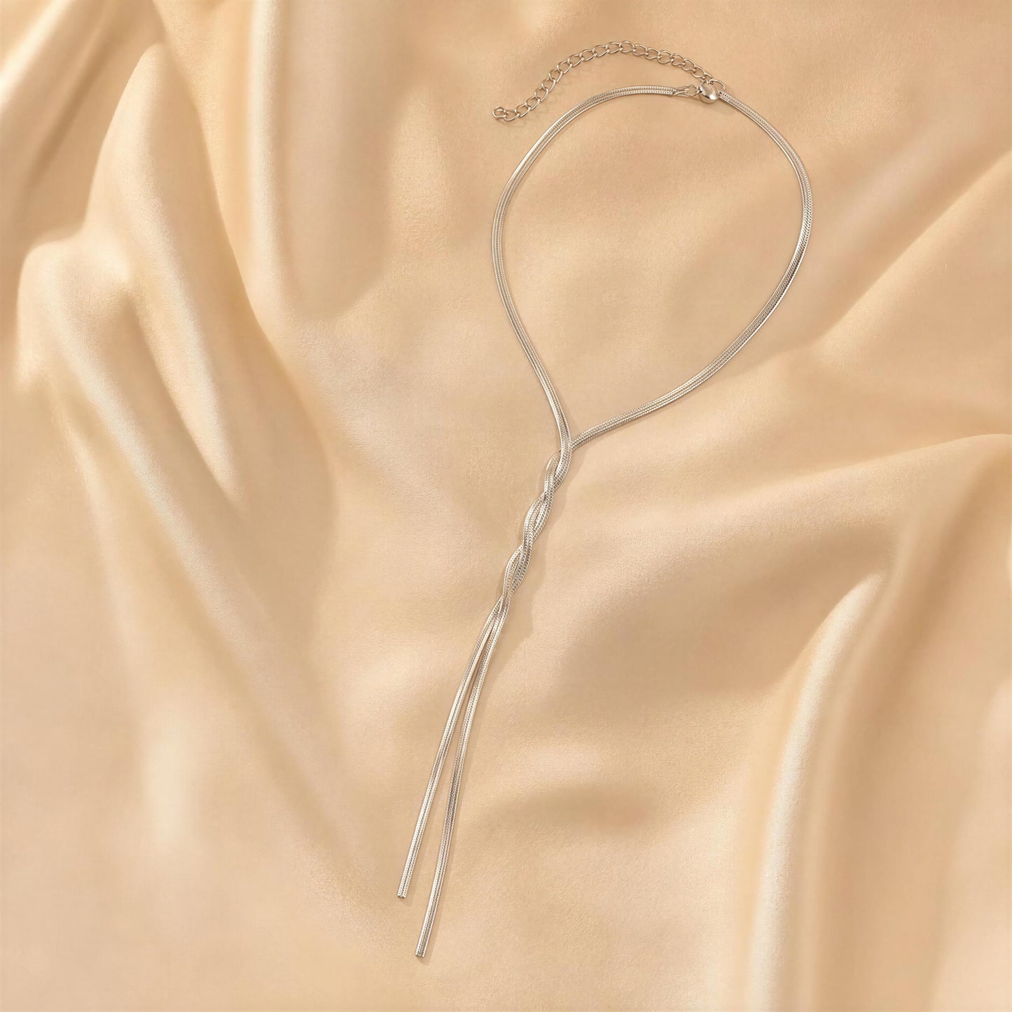 The Eterna Lariat Necklace - Silver on a beige fabric background