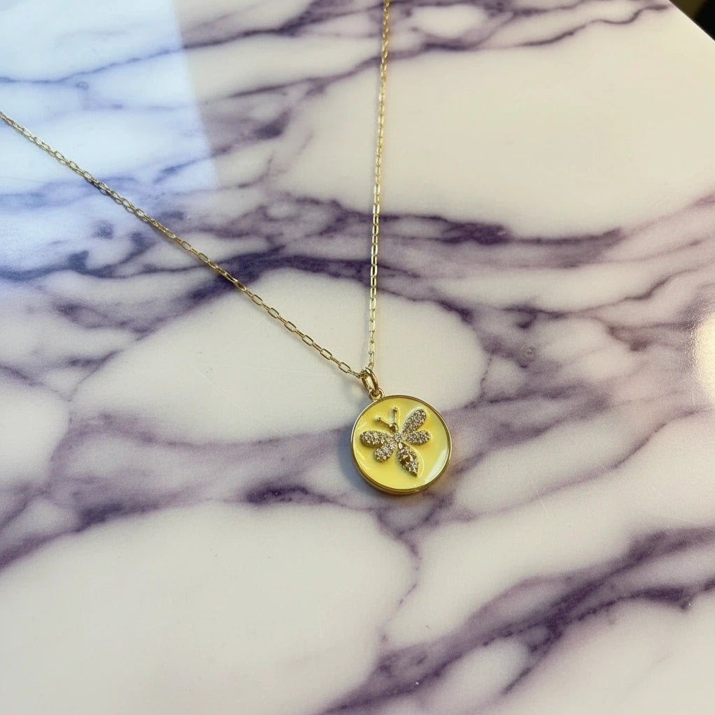 Gold necklace with a round pendant on a marble surface from Chica Chica Jewelry