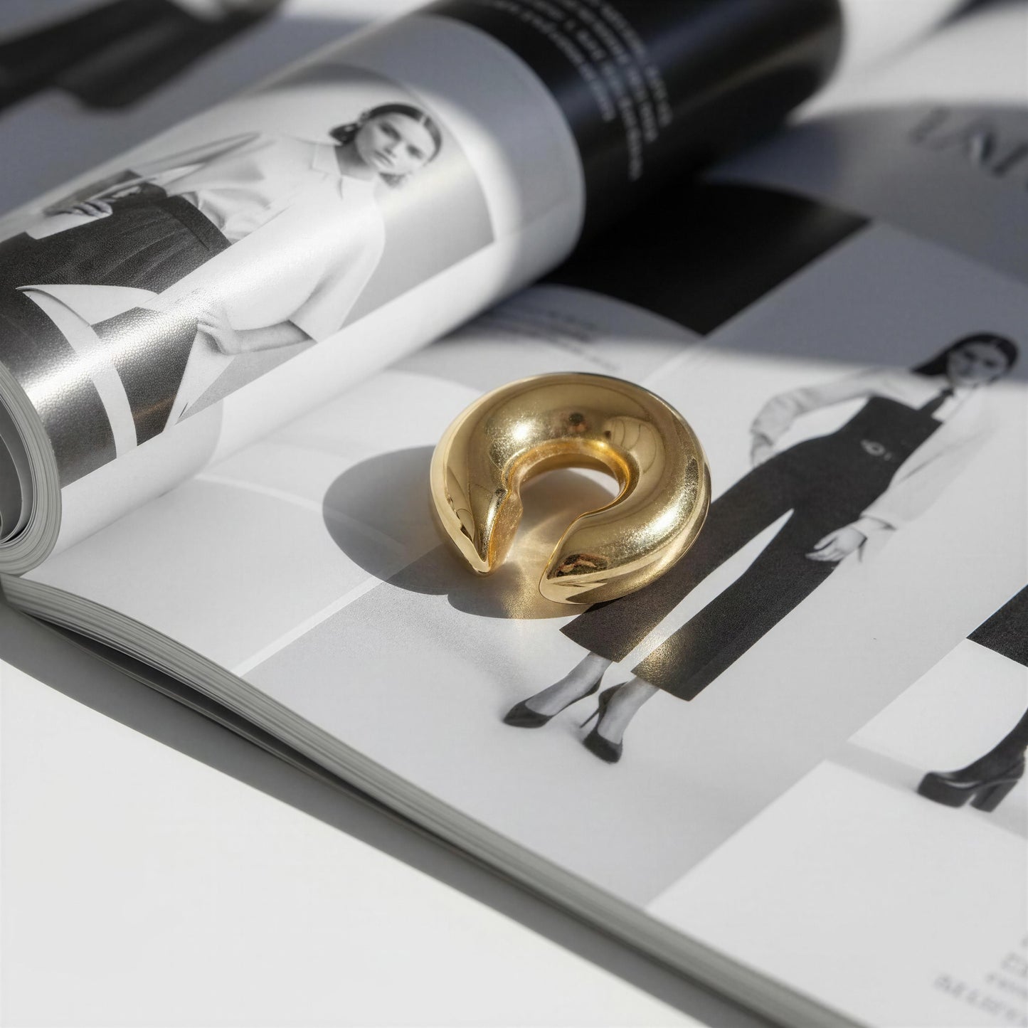 Lunar Orbit Ear Cuff on an open magazine with black and white photos