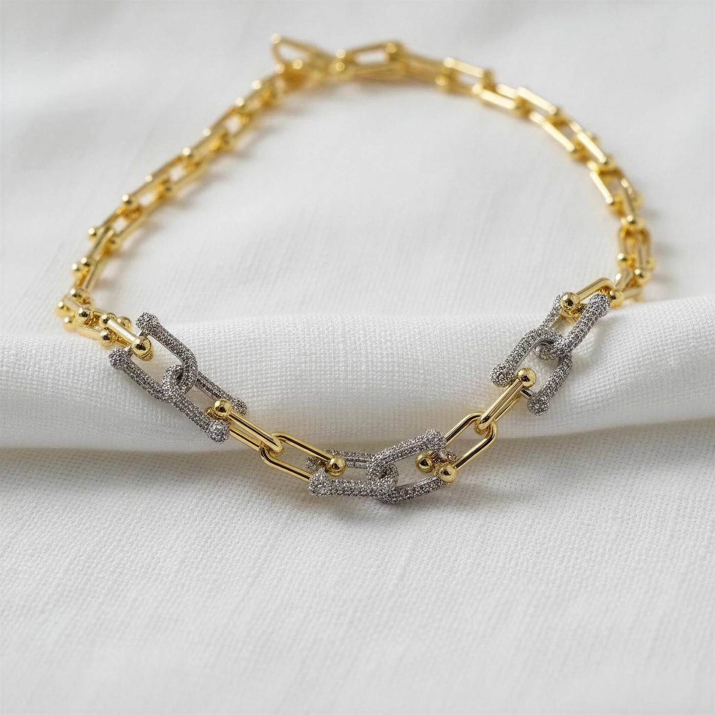 Gold and silver chain bracelet on a white fabric background