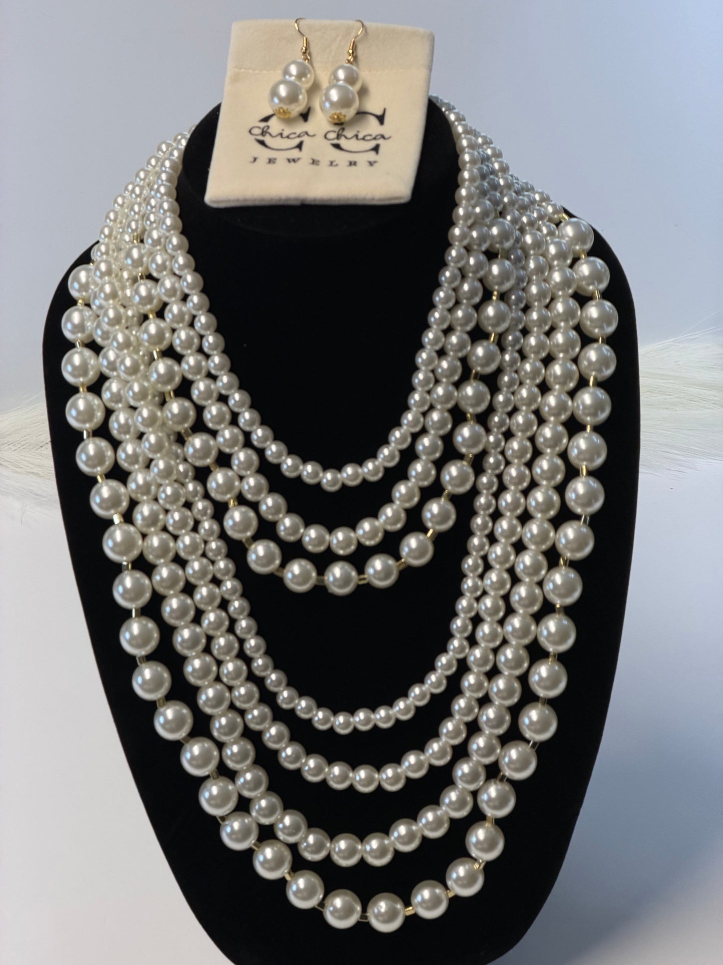 Pearl necklace displayed on a mannequin head with a neutral background