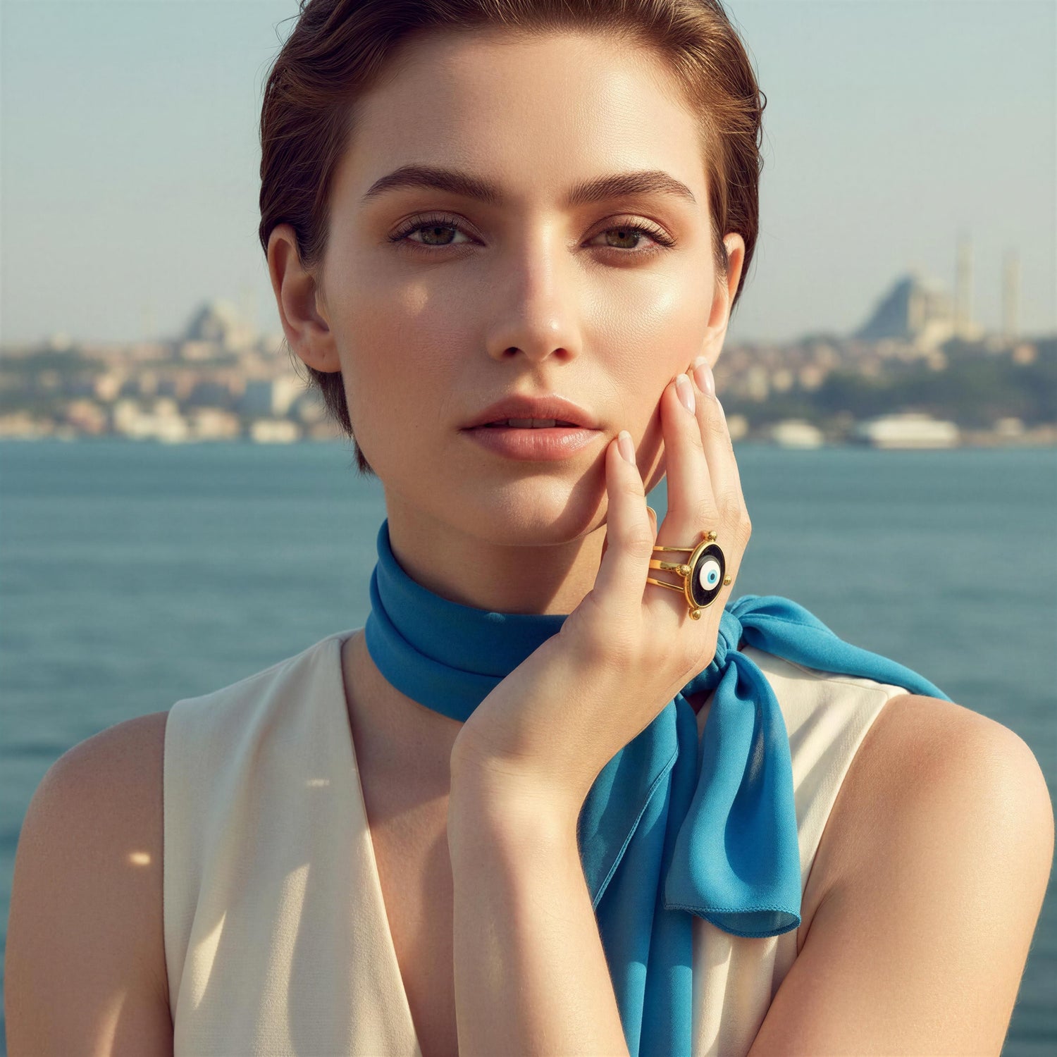 Woman wearing gold statement jewelry from Aegis Collection by Chica Chica Jewelry, elegant coastal background