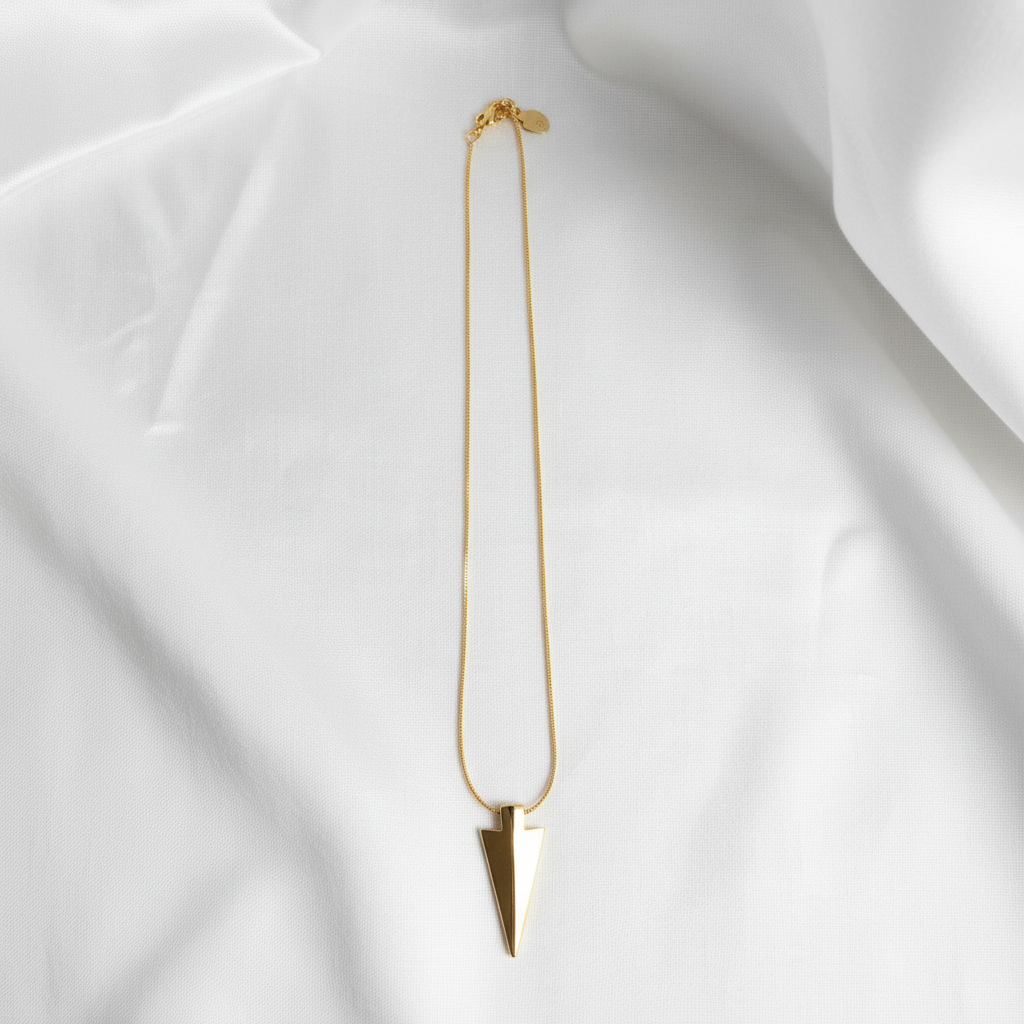 AXIS Arrow Necklace from Chica Chica Jewelry™ on a white fabric background