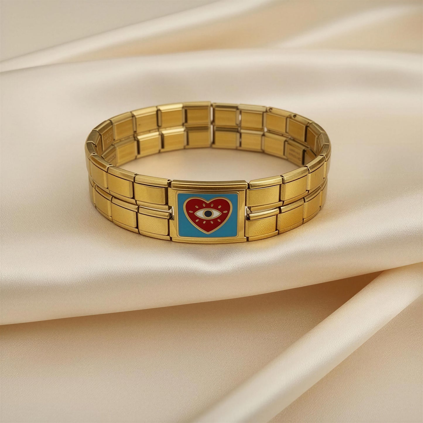 Gold Italian bracelet with a heart-shaped charm featuring an eye on a beige fabric background