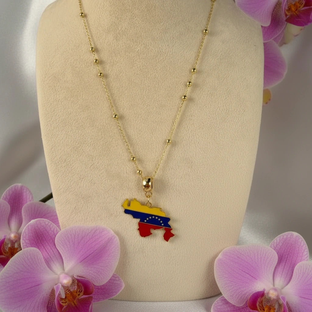 The Alma Llanera Necklace with a colorful Venezuela map pendant on a mannequin bust surrounded by pink orchids.