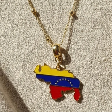 The Alma Llanera_Necklace from the _Roots_Heritage_Collection-_Chica Chica_Jewelry with the Venezuela flag pendant on a textured beige background
