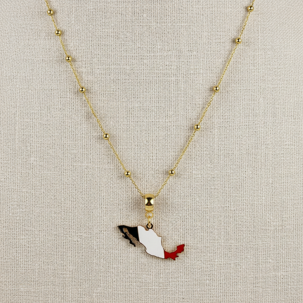 The Alma Mexicana Necklace with a the flag pendant on a beige fabric background