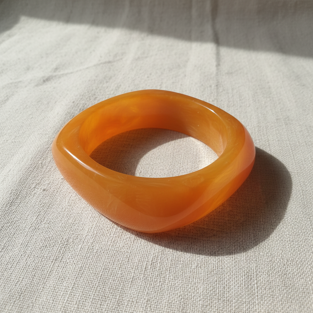 Orange Amber Glow Bangle on a textured beige fabric background