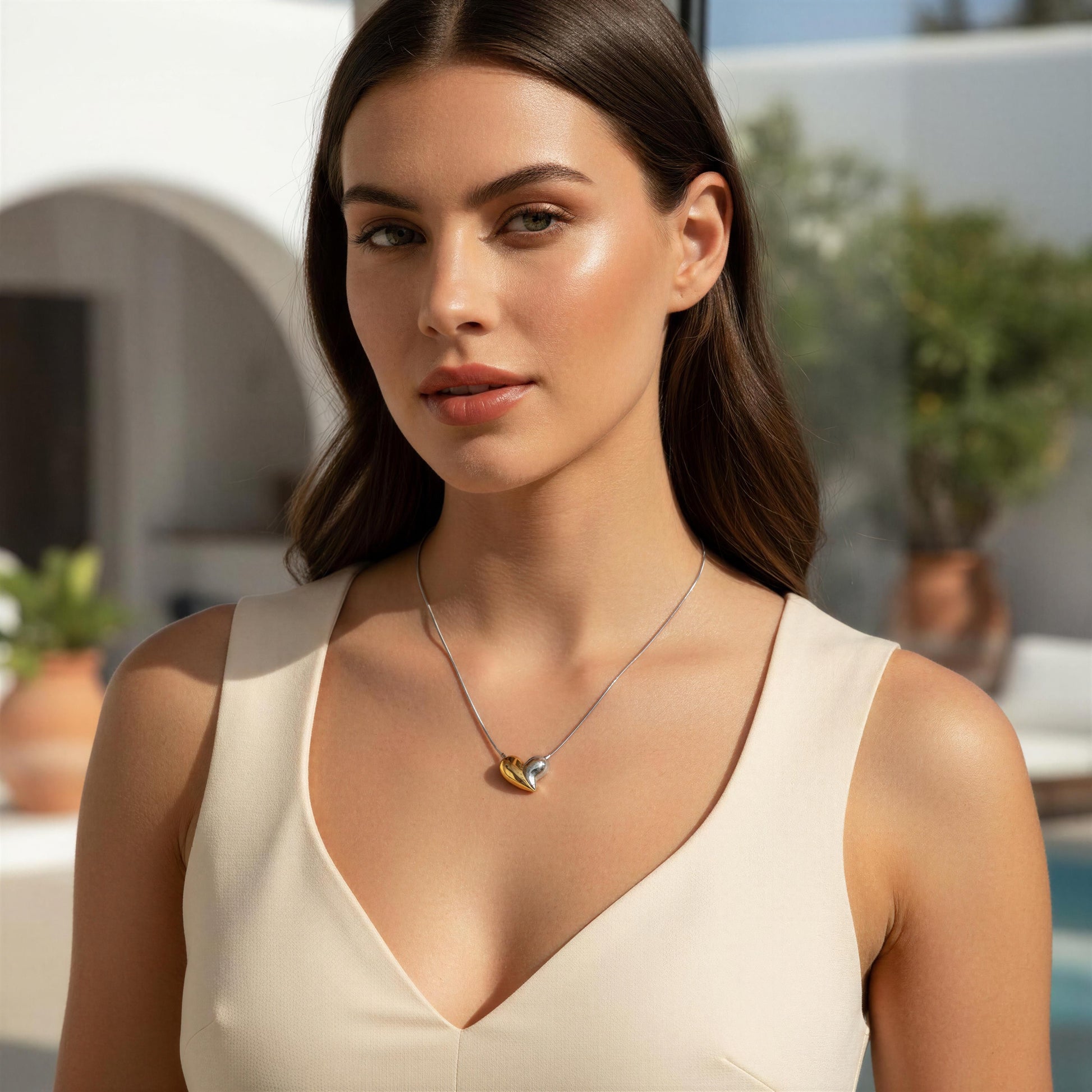 Woman wearing the Amor Eterno Necklace with a heart pendant in an outdoor setting 