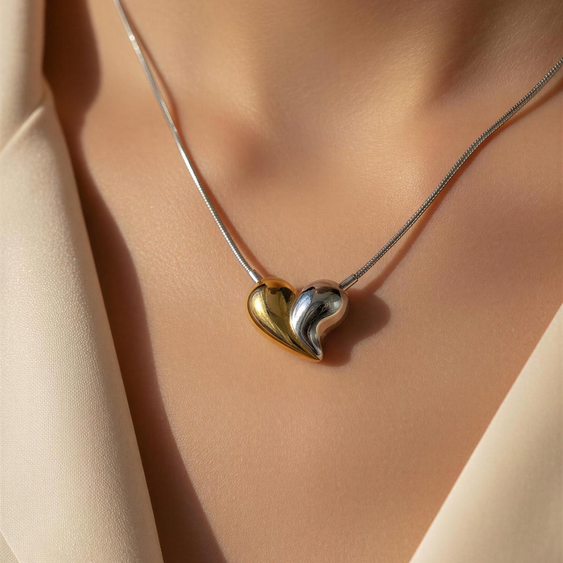 Heart-shaped pendant necklace on a person wearing a beige outfit