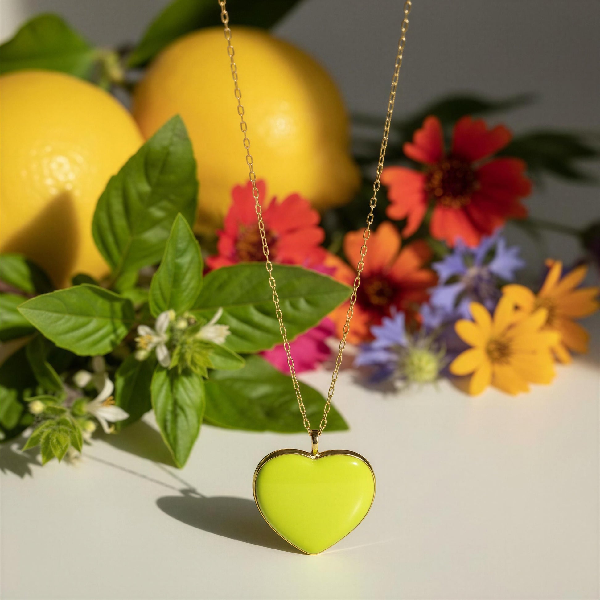The Limoncello Heart Necklace with lemons and flowers in the background.