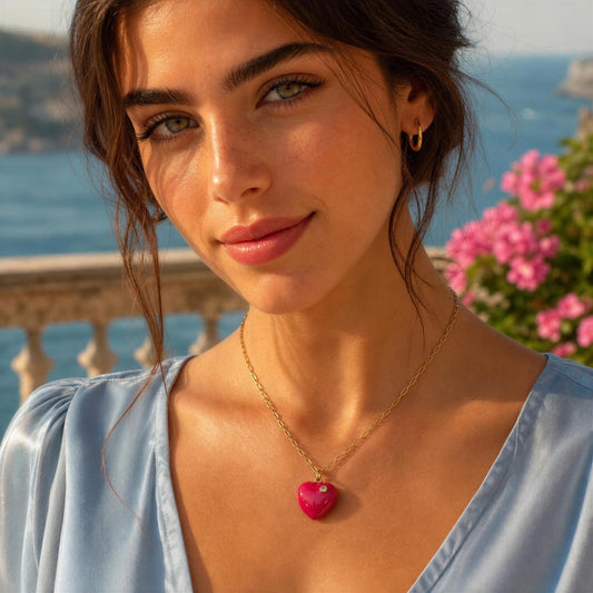Woman wearing a gold necklace with a heart pendant in front of a scenic background