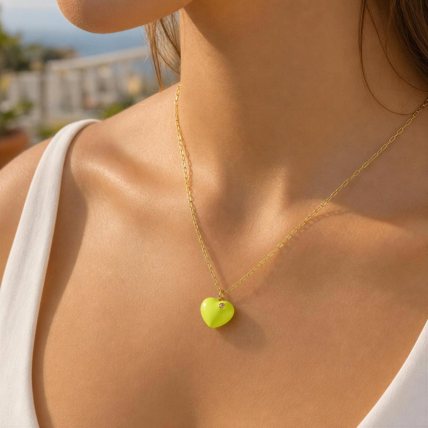 The Amore Lemon Glow Heart Necklace worn by a person outdoors.