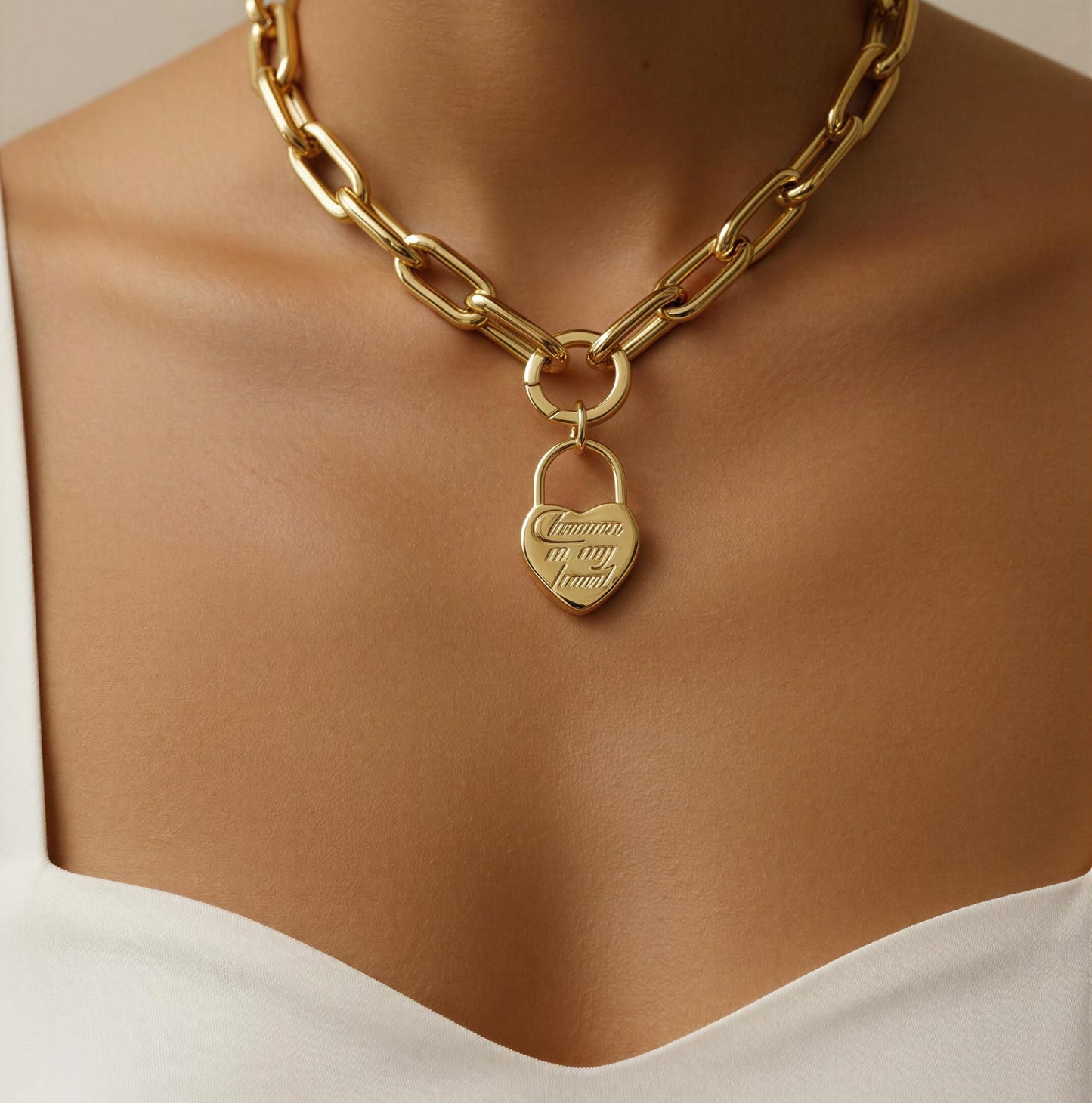 Gold chain necklace with a heart padlock pendant on a neutral background