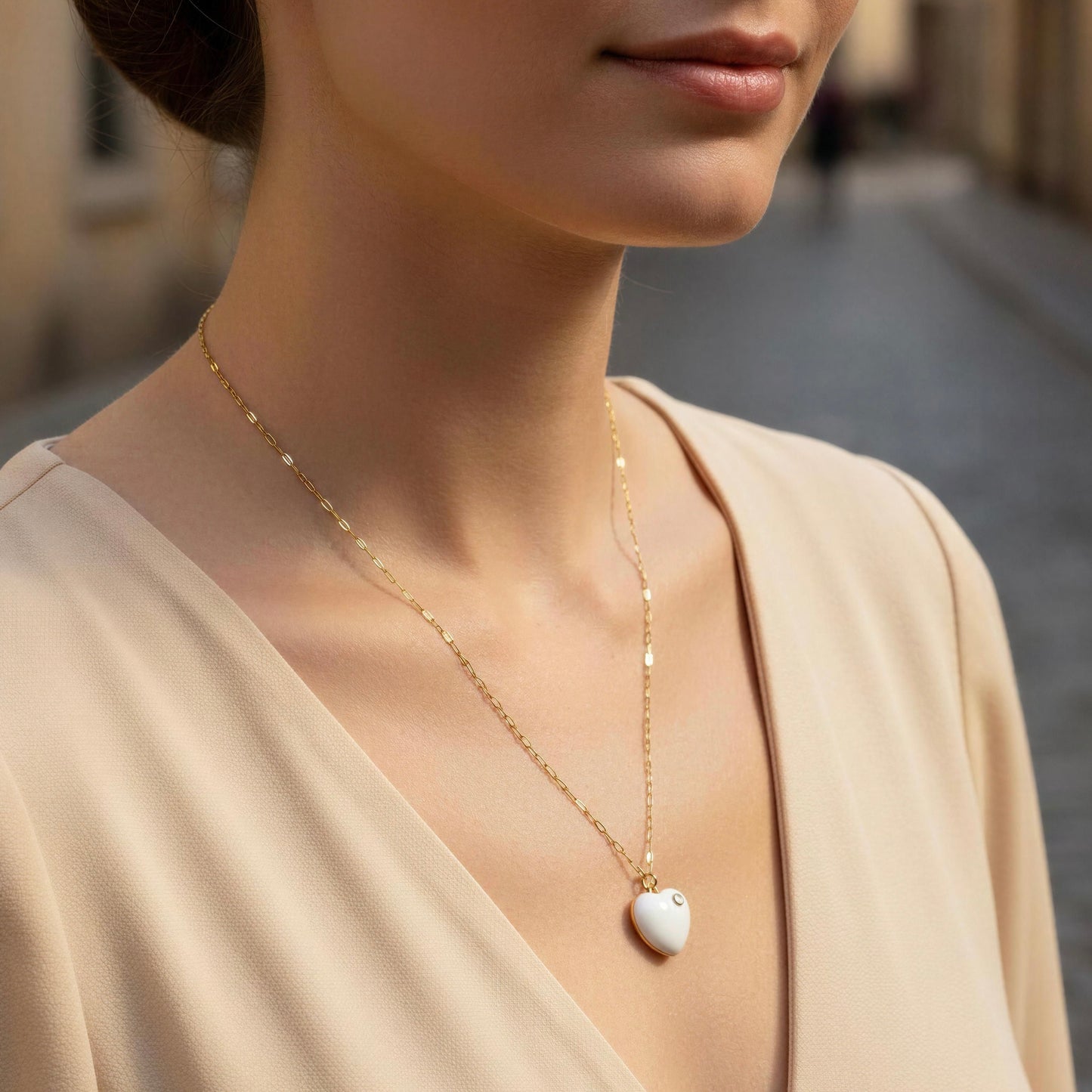 Close-up of a woman wearing a delicate gold necklace with a heart-shaped pendant.