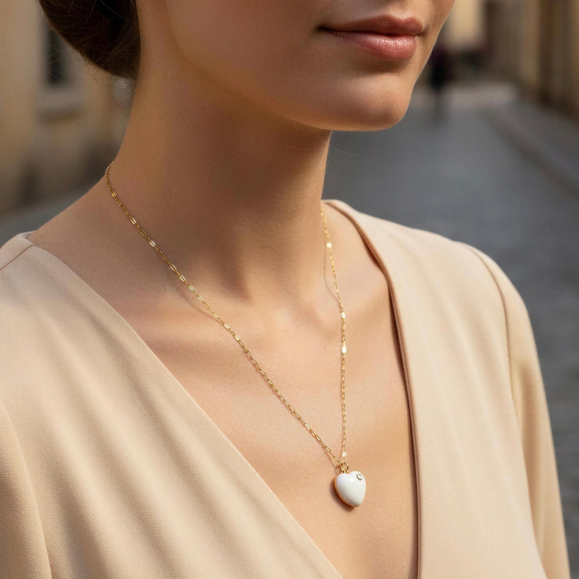 Close-up of a woman wearing a delicate gold necklace with a heart-shaped pendant.