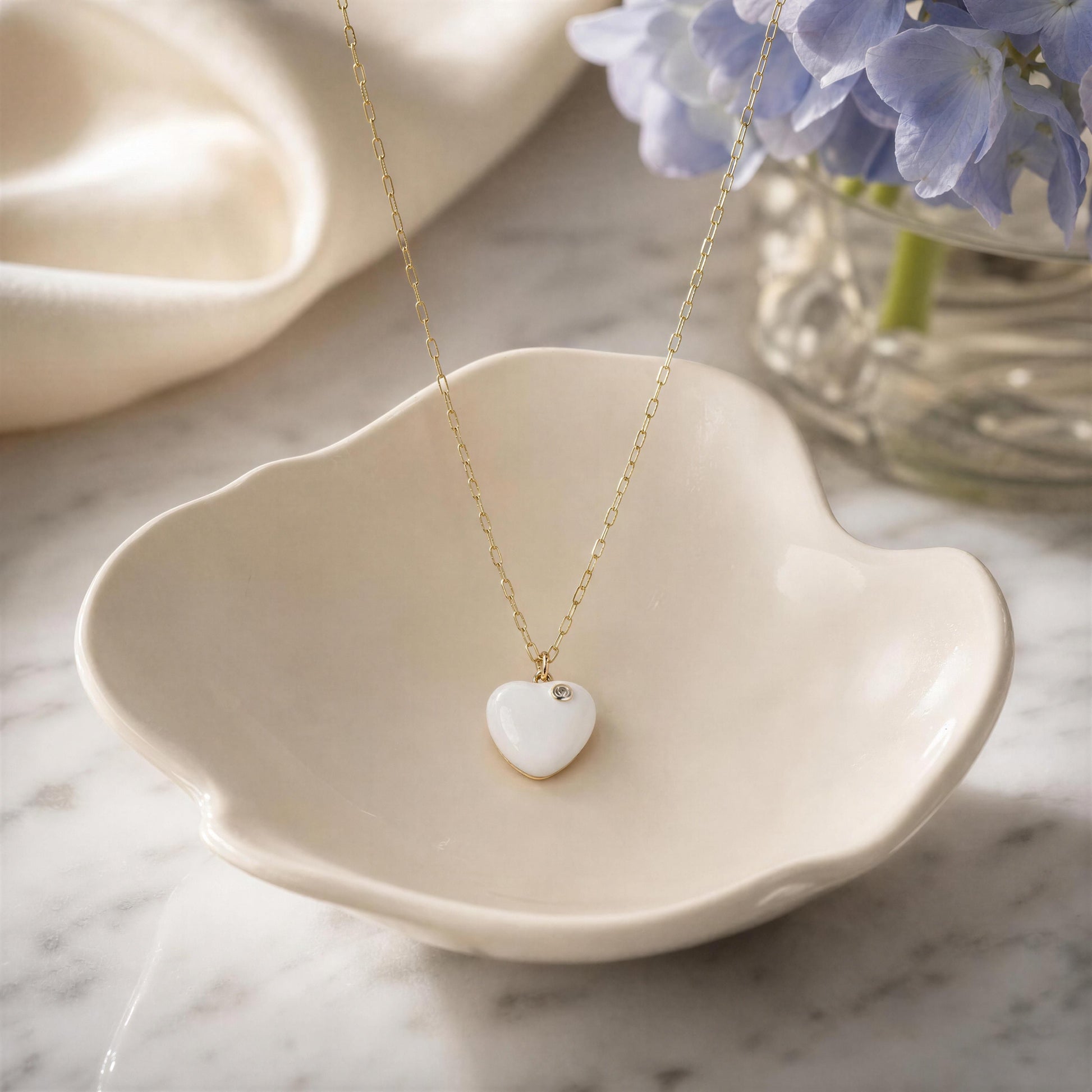 Necklace with a heart-shaped pendant on a decorative dish with flowers in the background