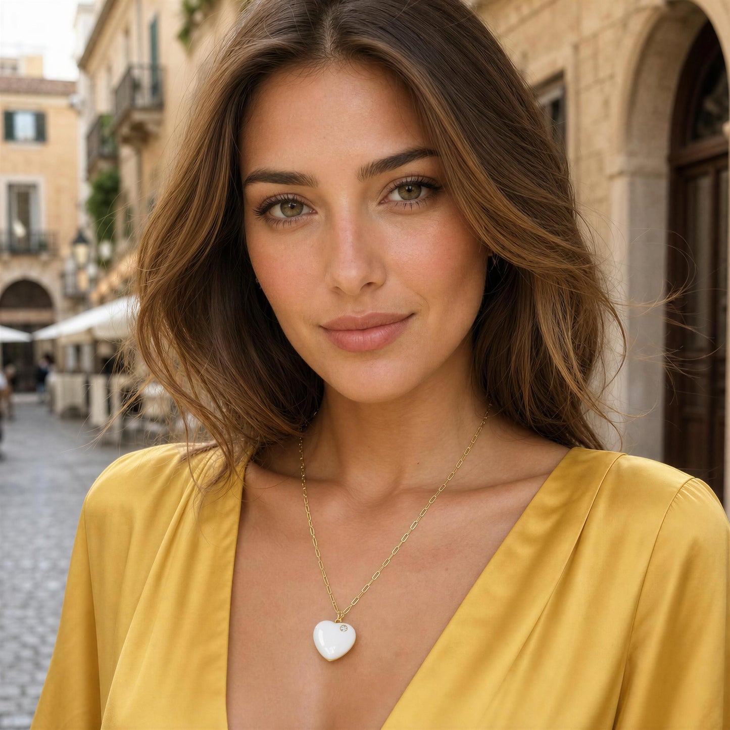 Woman wearing a yellow top with a heart-shaped necklace in an outdoor setting