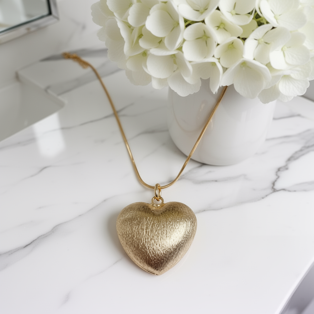 Amore Textura Heart Necklace from Chica Chica Jewelry  on a marble surface with white flowers in the background