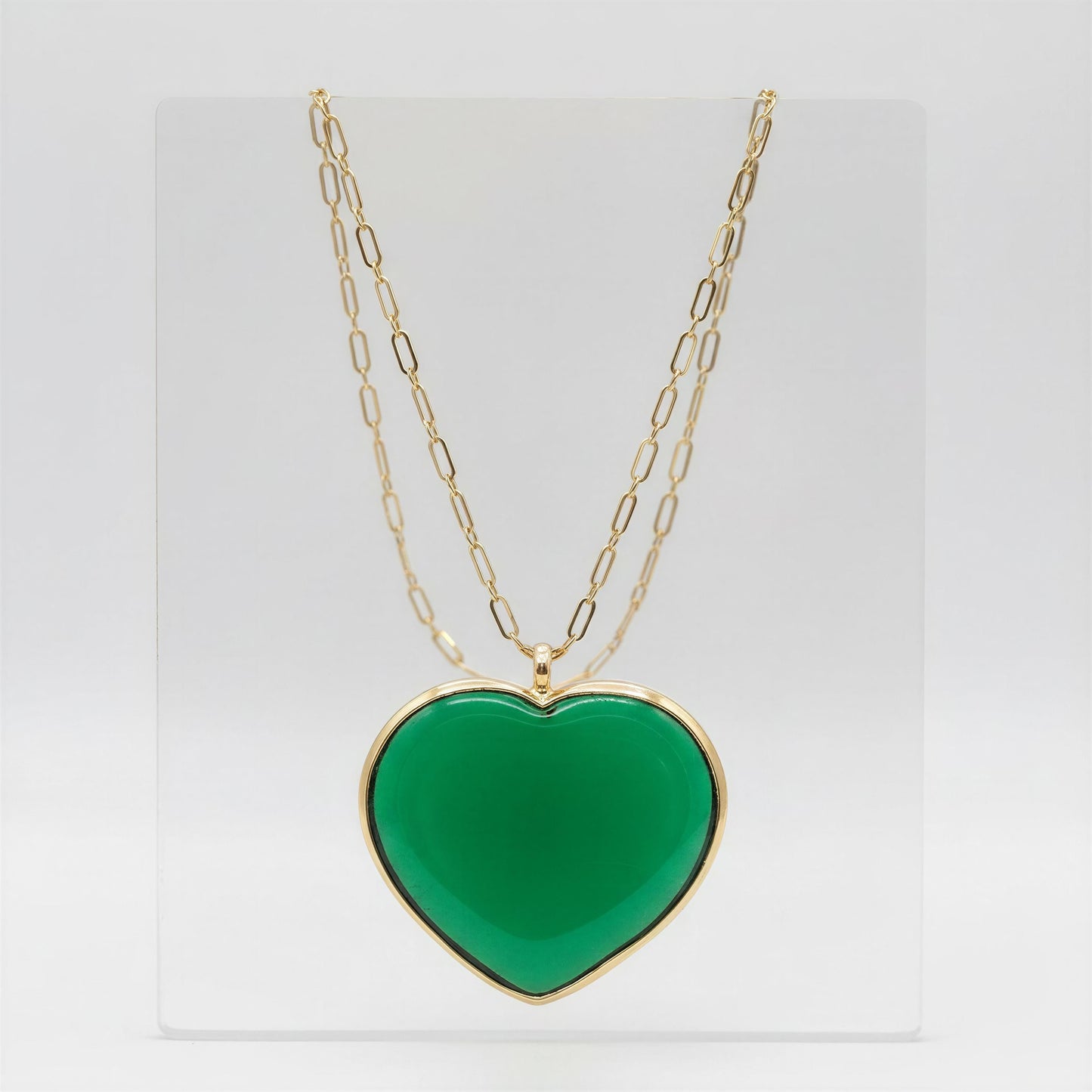 The Verde Murano Heart Necklace on a light gray crystal background