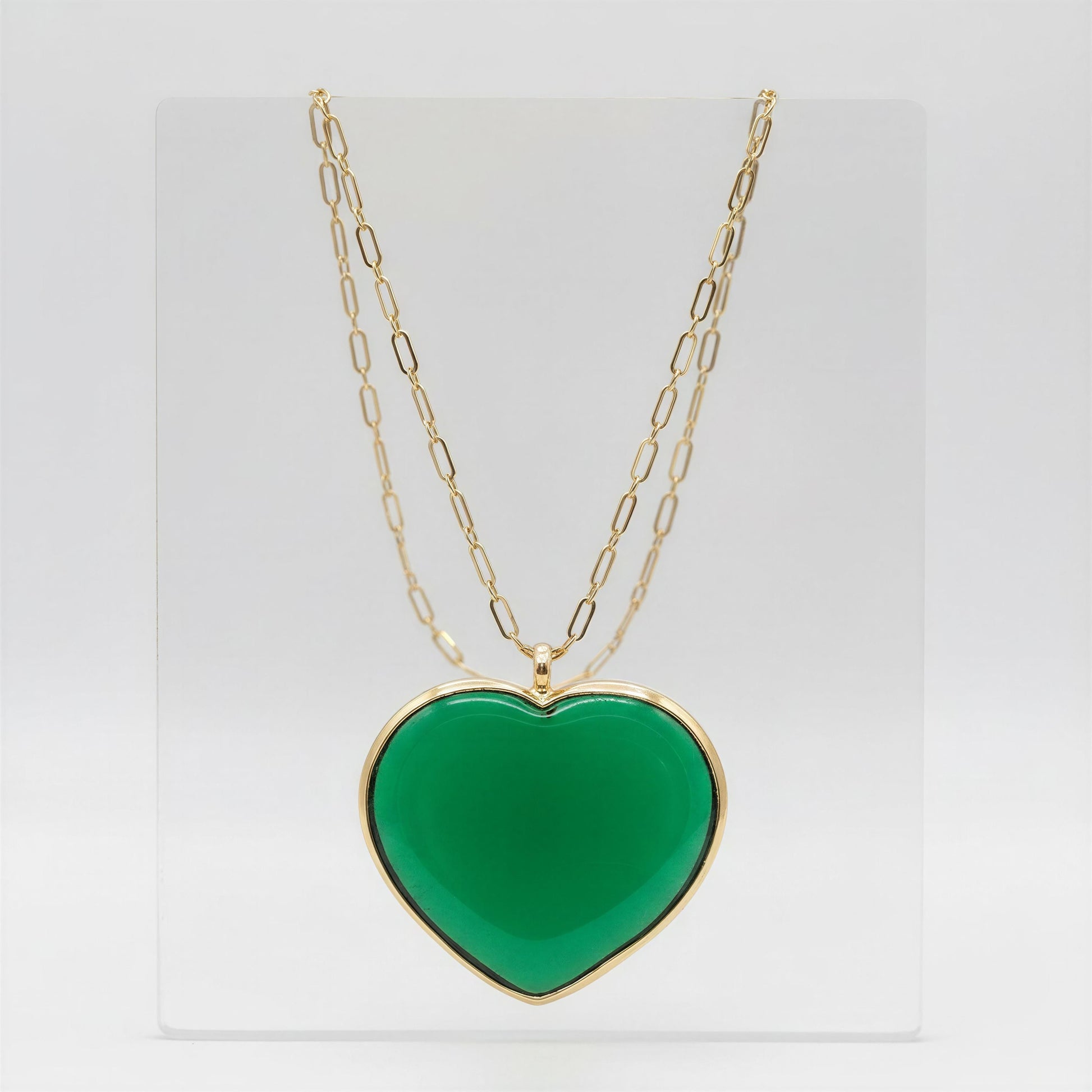The Verde Murano Heart Necklace on a light gray crystal background
