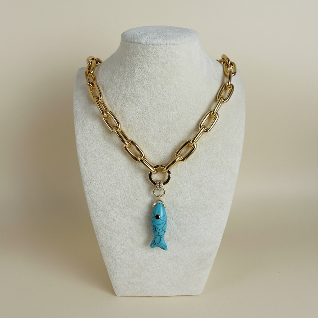 Gold chain necklace with a blue fish pendant on a white mannequin bust.
