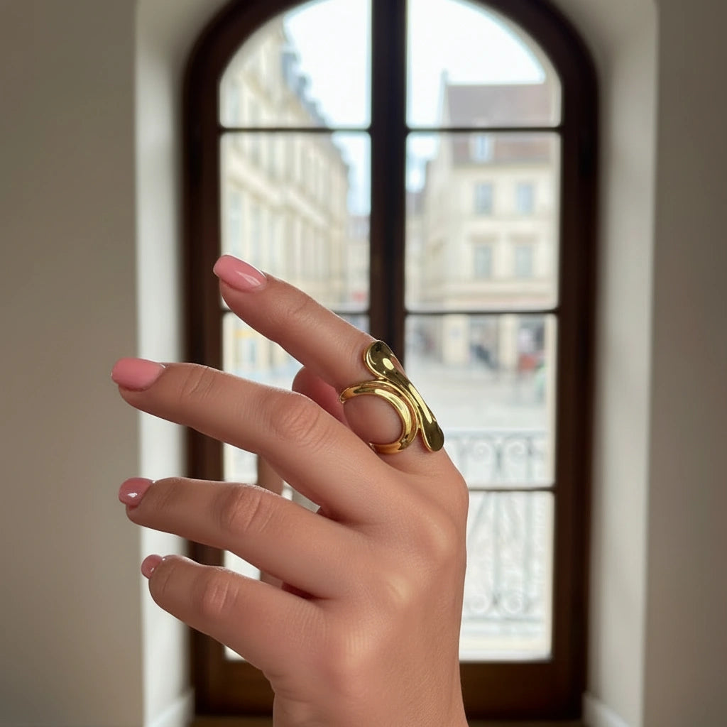 Hand wearing the Aurea Ring with a blurred window in the background