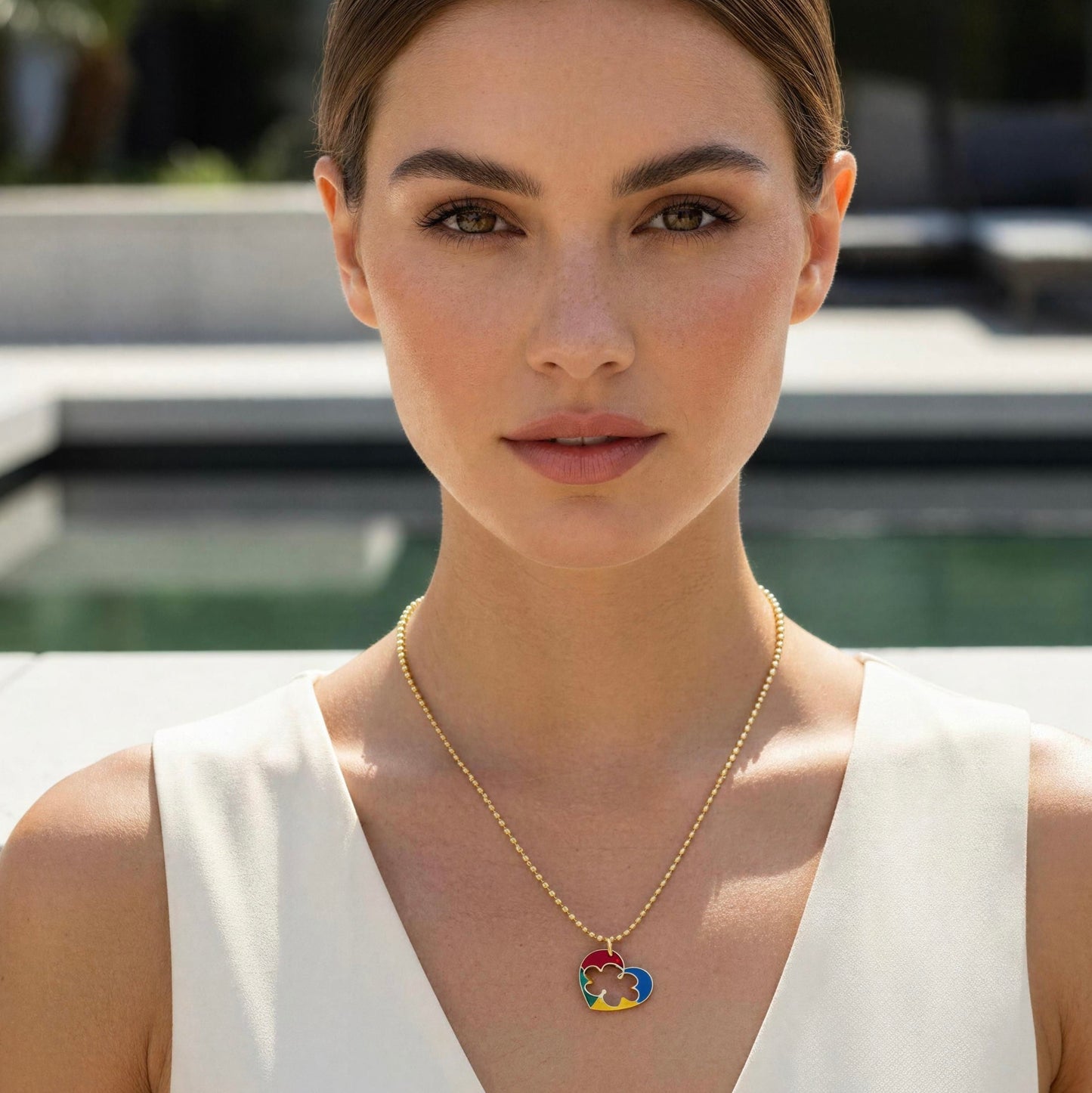 Woman wearing the Autism Connection Heart Set – Gold Beaded Bracelet  with a colorful heart pendant outdoors