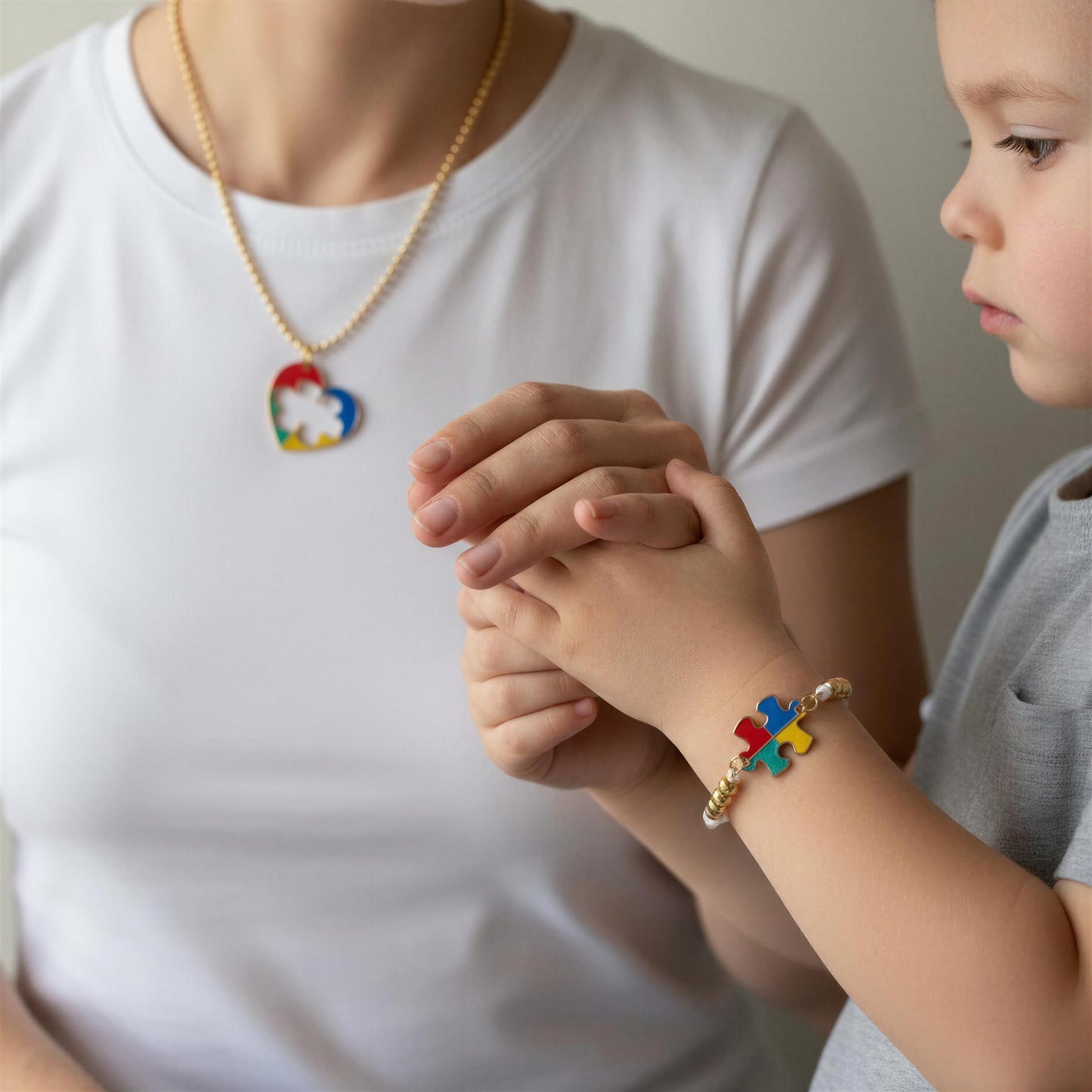 Person and child holding hands, both wearing the Autism Connection Heart Set – White Cord Edition