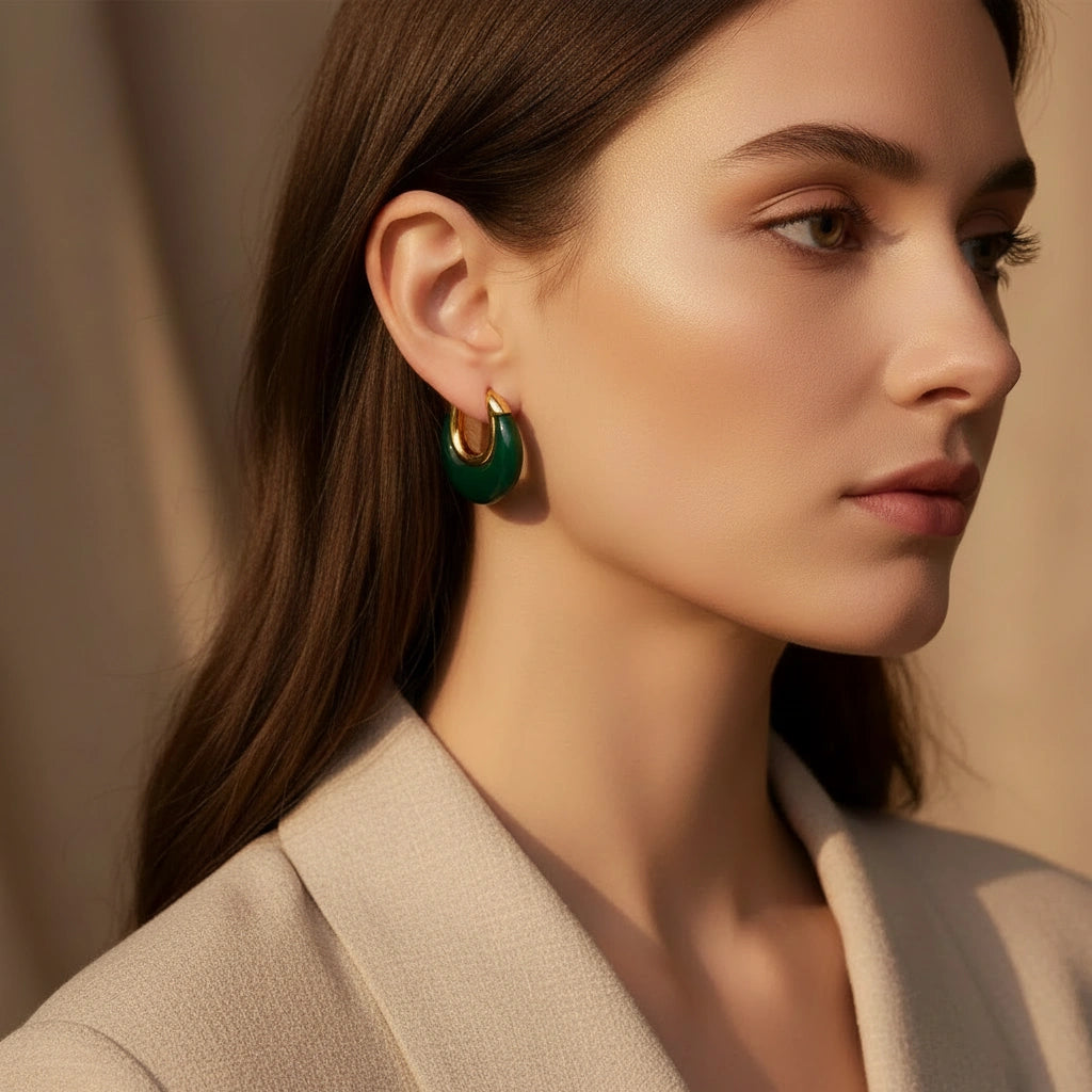 Close-up of a woman wearing green hoop earrings with a neutral background