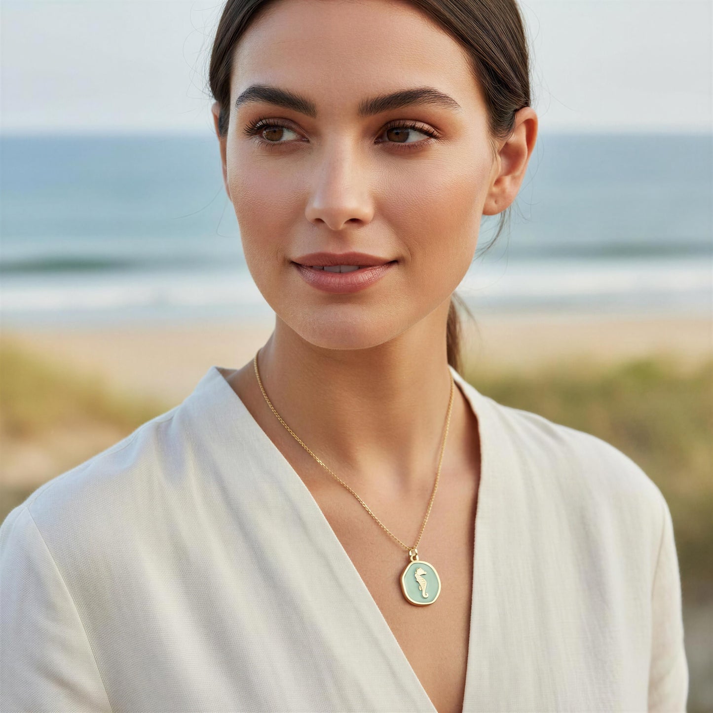Woman wearing the Azure Seahorse Necklace on a beach