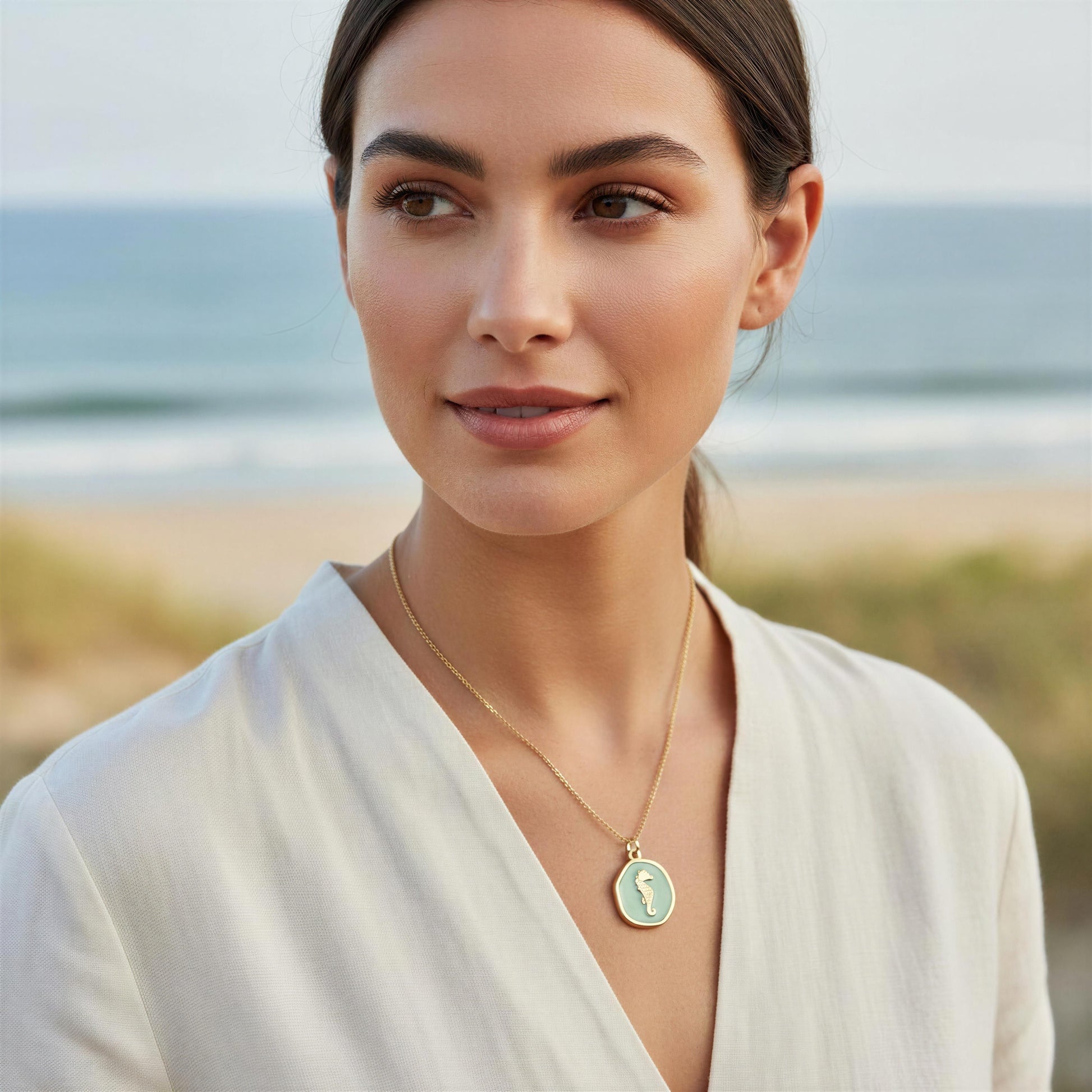 Woman wearing the Azure Seahorse Necklace on a beach