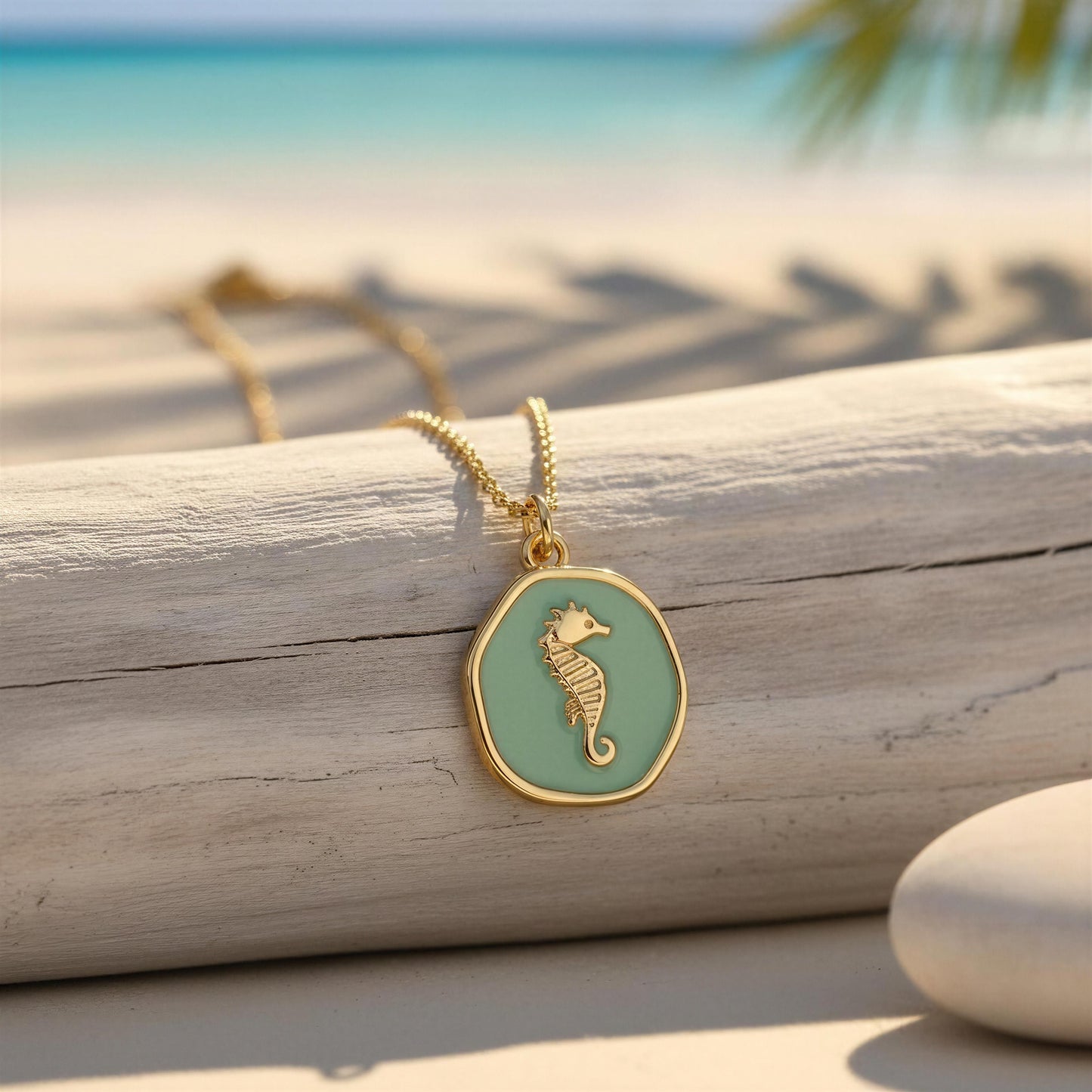 Gold necklace with a seahorse pendant on a wooden log by the beach