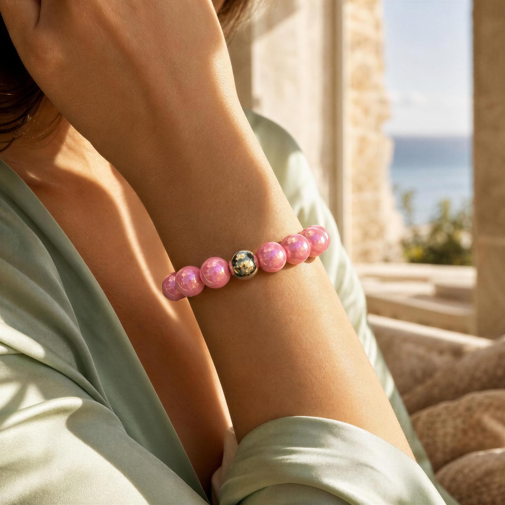 Person wearing the Ballet Glow Bracelet with a gold accent by a Mediterranean terrace