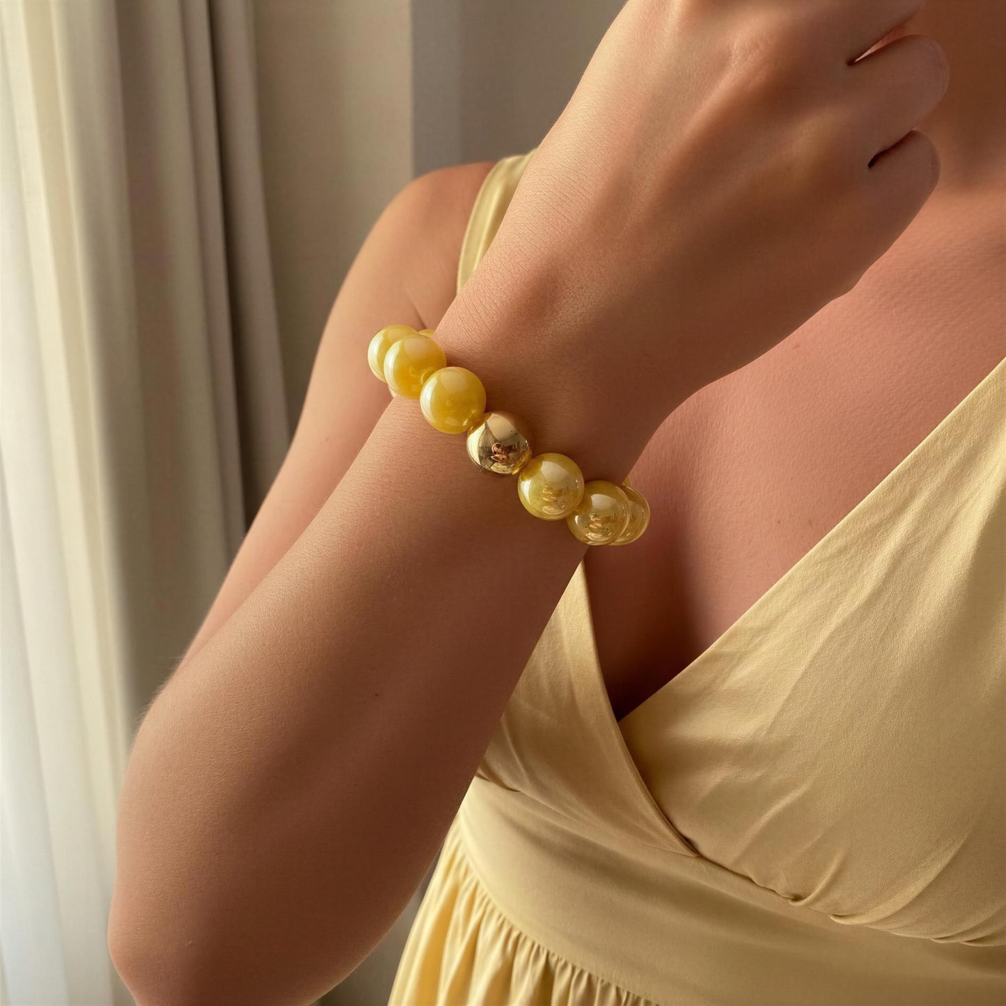 Woman wearing a yellow beaded bracelet with a neutral background