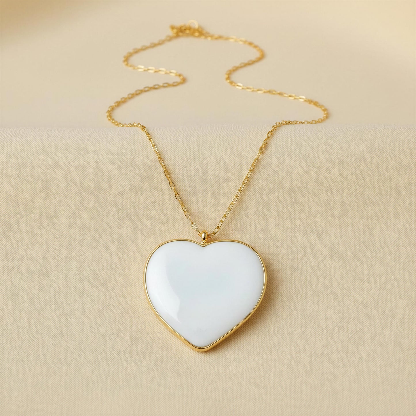 The Bianca Heart Necklace with gold chain on beige background