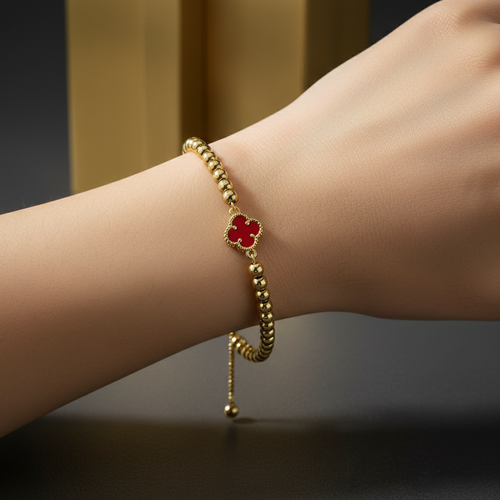 The Eterna Mini Red Clover Adjustable Bracelet with a red flower charm on a wrist against a dark background