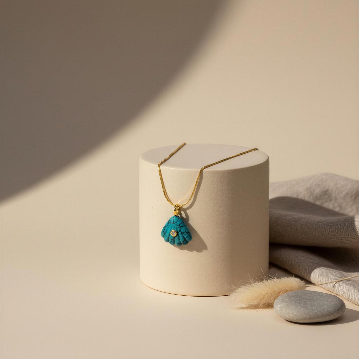 Turquoise pendant necklace on a white cylindrical stand with a neutral background