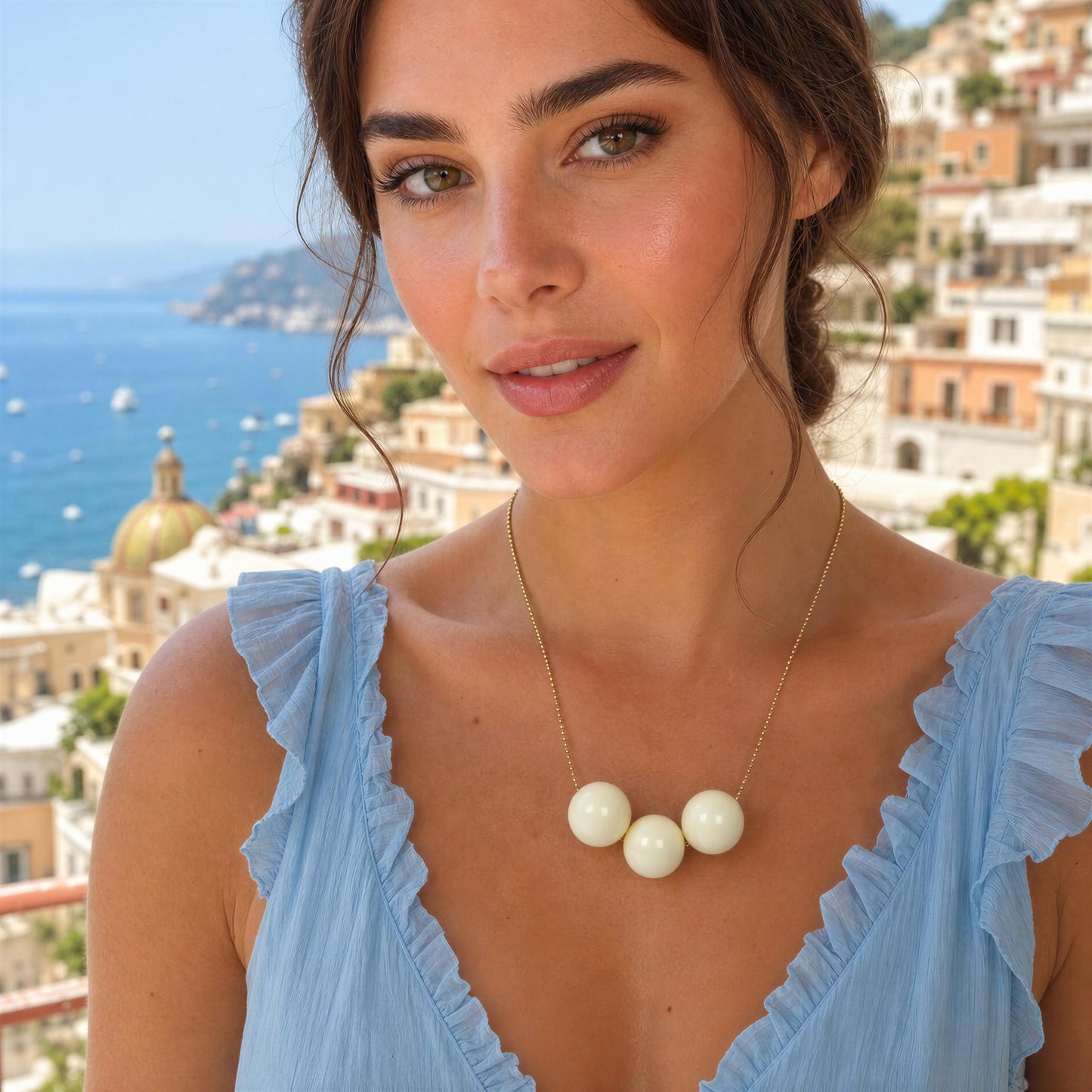 Woman wearing a blue dress with ruffled shoulders and the Calla Necklace from Chica Chica Jewelry  against a scenic background.