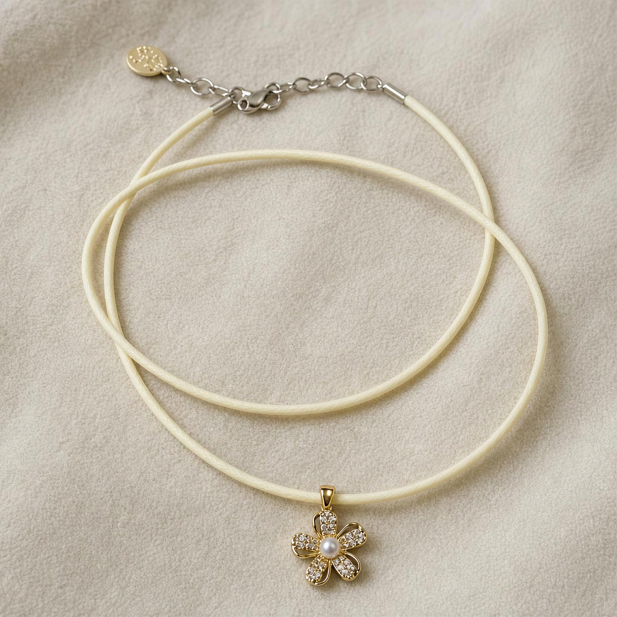 The Camellia Necklace from Chica Chica Jewelry against crème fabric. 
