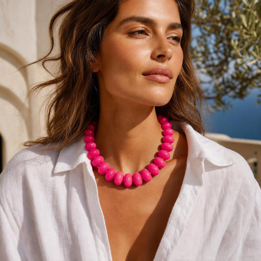 Woman wearing a bright pink necklace with a scenic background