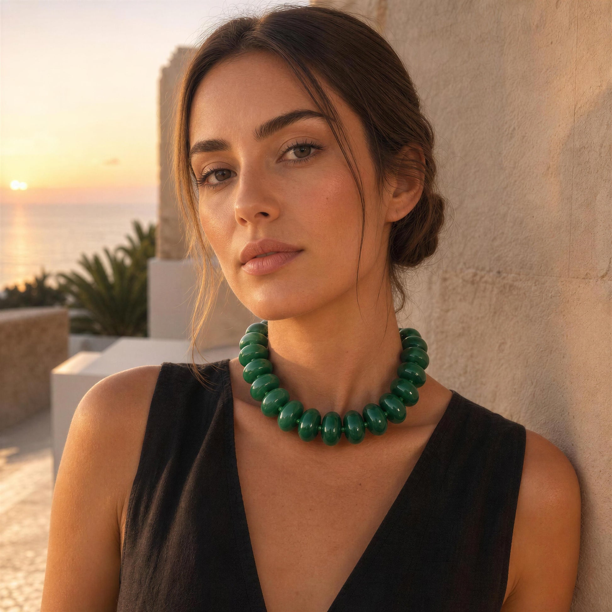 Woman wearing a green necklace with a sunset and beach in the background