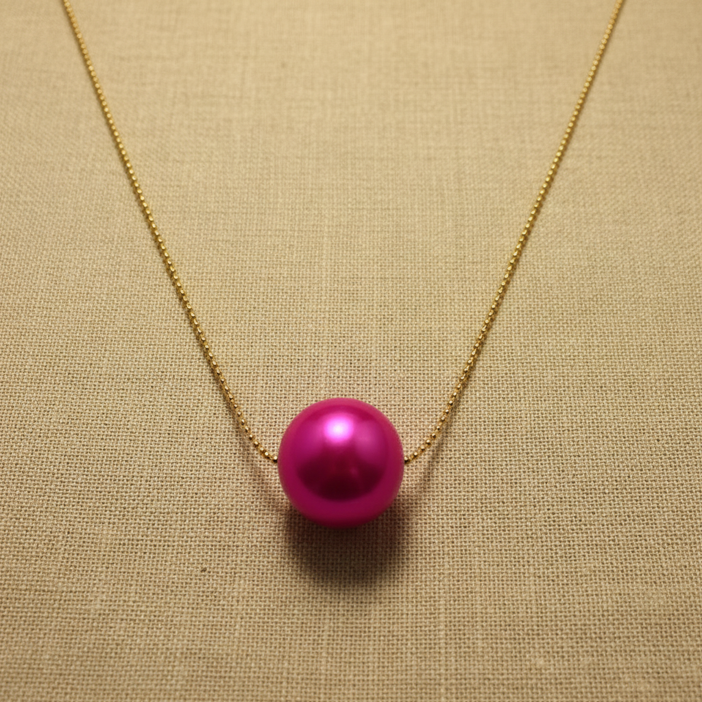 The Carmin Petite Sphere Necklace from Chica Chica Jewelry  on a beige fabric background
