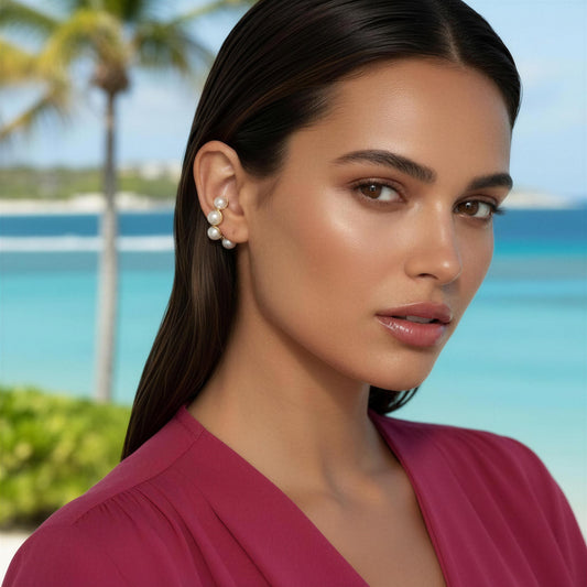 Woman wearing the Celestial Pearl Cuff with a beach and palm tree in the background
