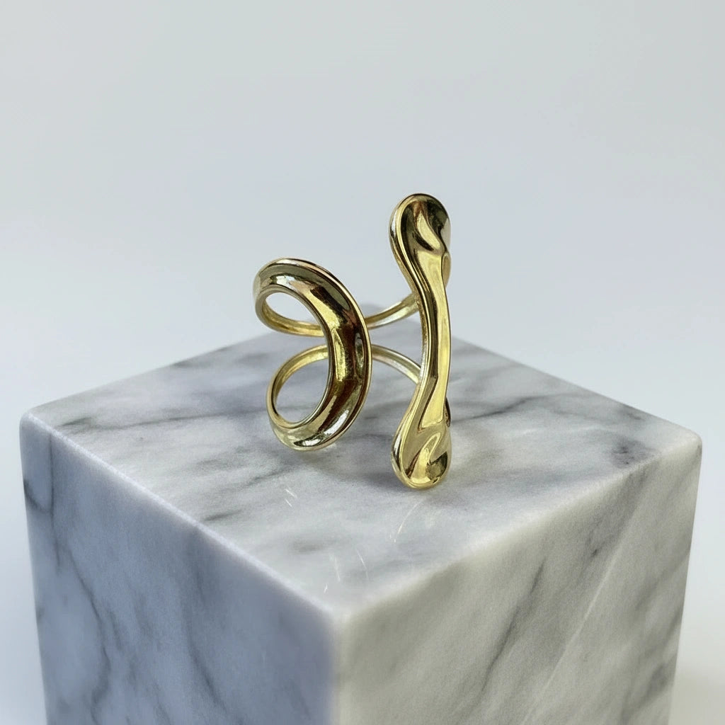 Gold spiral ring on a marble pedestal with a light gray background