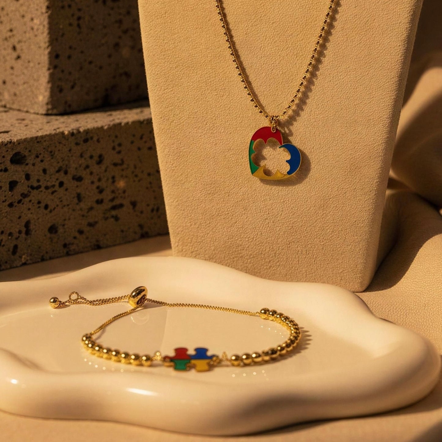 The Autism Connection Heart Set – Gold Beaded Bracelet with colorful heart pendants on a textured surface